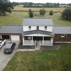 Brick home with black metal roof by Bontrager Roofing LLC