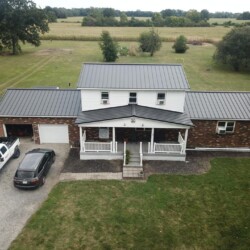 Brick home with black metal roof by Bontrager Roofing LLC